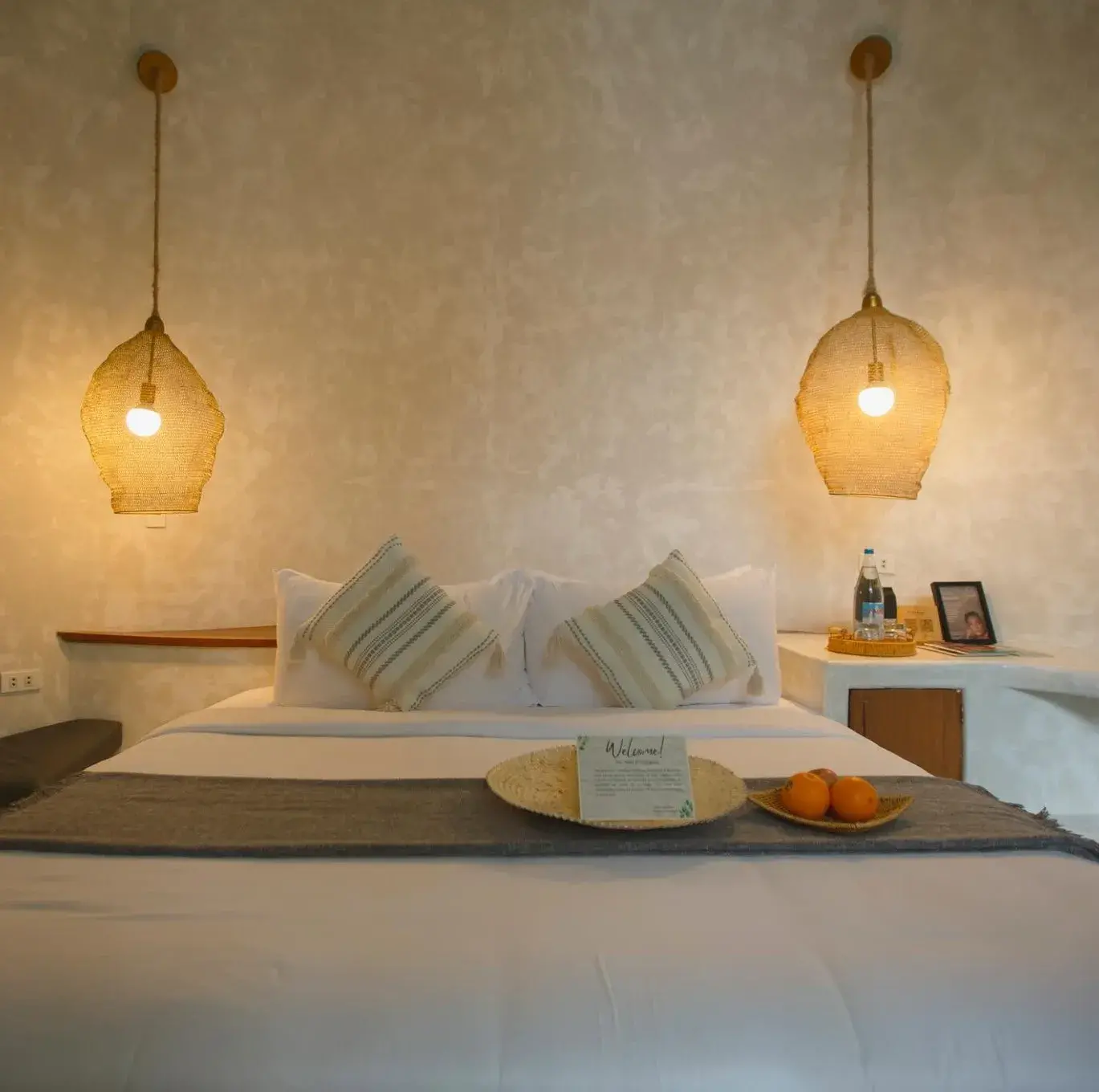 Suite Deluxe : lit avec des coussins rayés et un plateau d'oranges