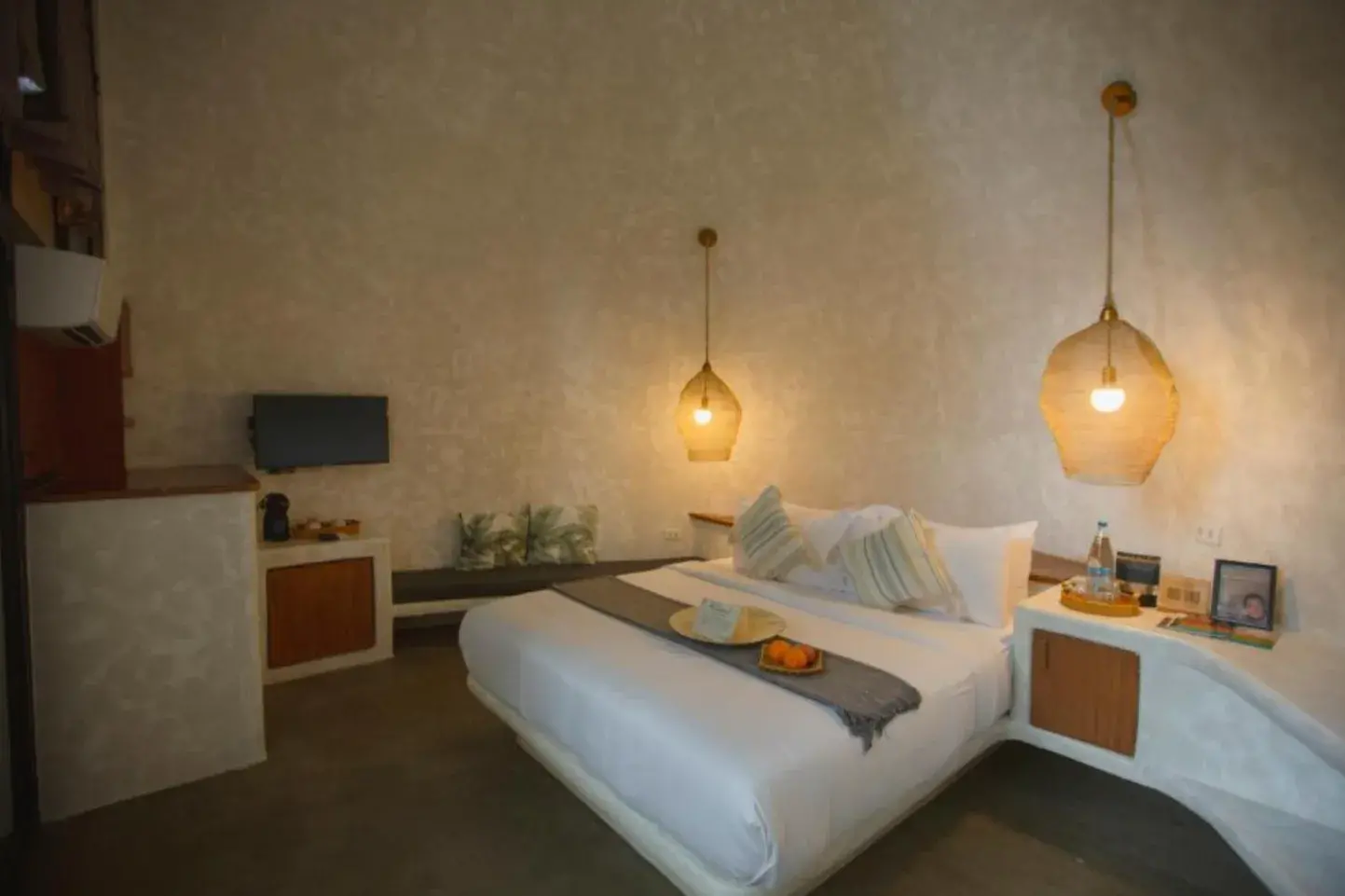 Suite Deluxe avec télévision, meubles en bois et lit en linge blanc sous des suspensions