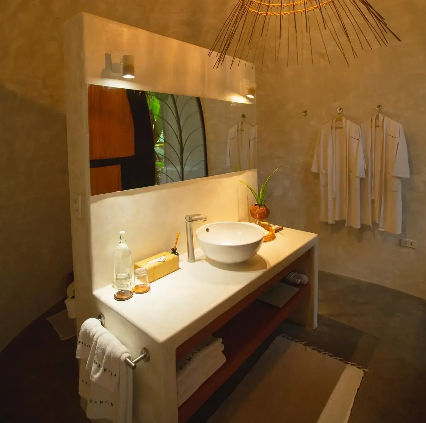 Salle de bain de la Suite Deluxe avec vasque, miroir et deux peignoirs